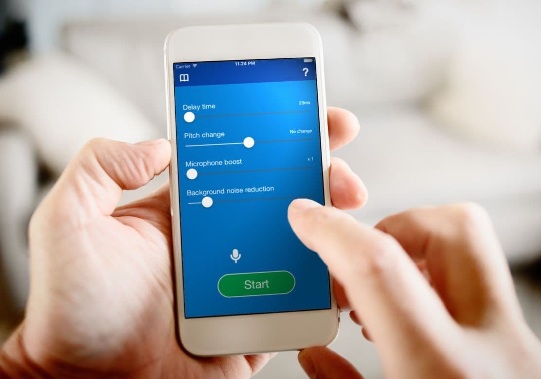 A photo of the DAF Pro app on an iPhone. A person is holding it in two hands and using one finger to tap the screen.