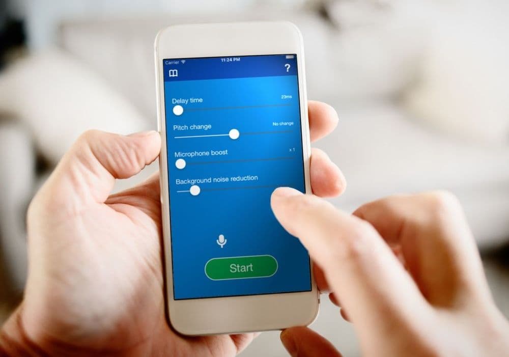 A photo of the DAF Pro app on an iPhone. A person is holding it in two hands and using one finger to tap the screen.