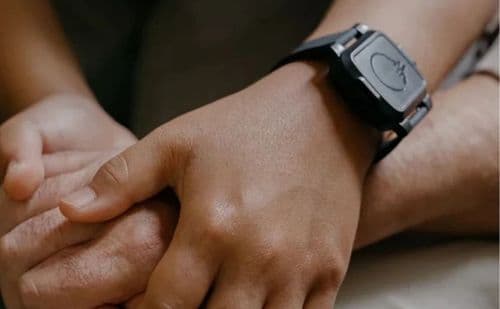 A close up photo of two people holding hands. One has the BeechBand 100E on their wrist.