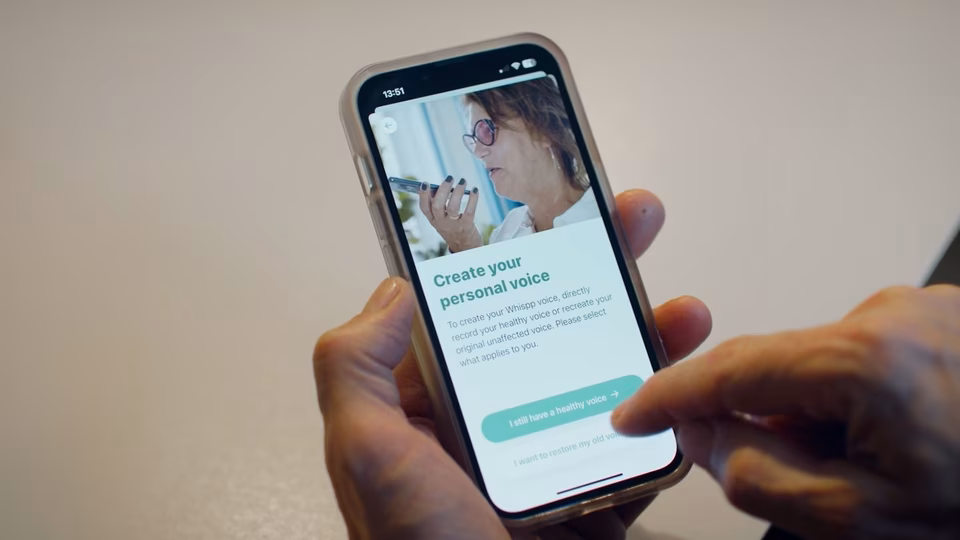 Someone using the app to "Create your personal voice". They are holding the smartphone in their hands.